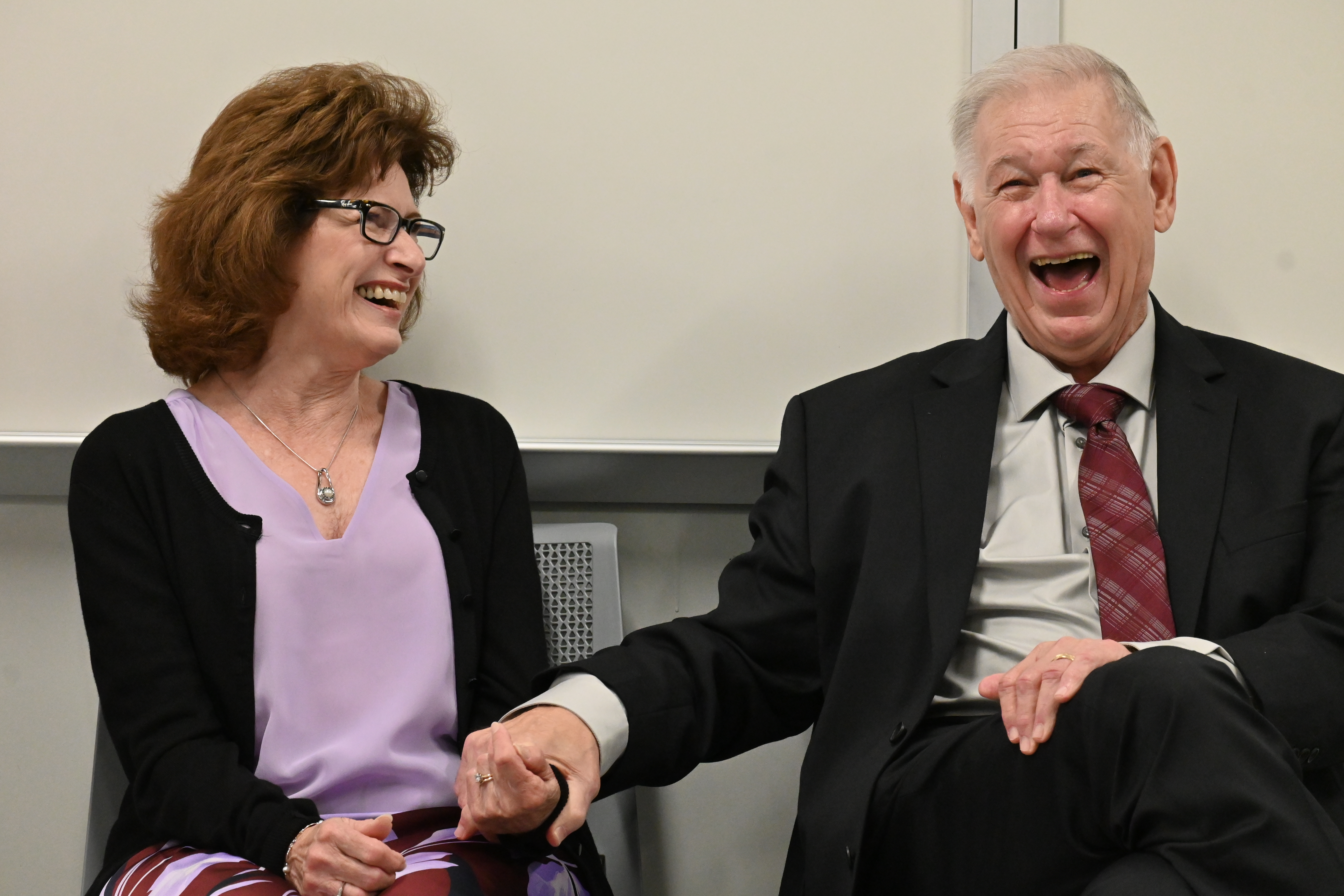 Linda, left, and Lew Myers, right, hold hands and laugh in a classroom.