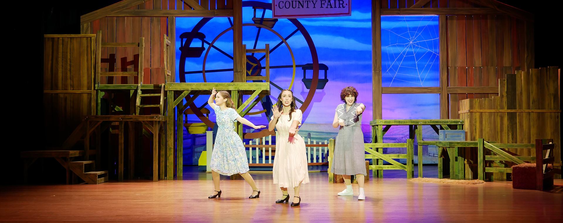 three actresses on stage dancing