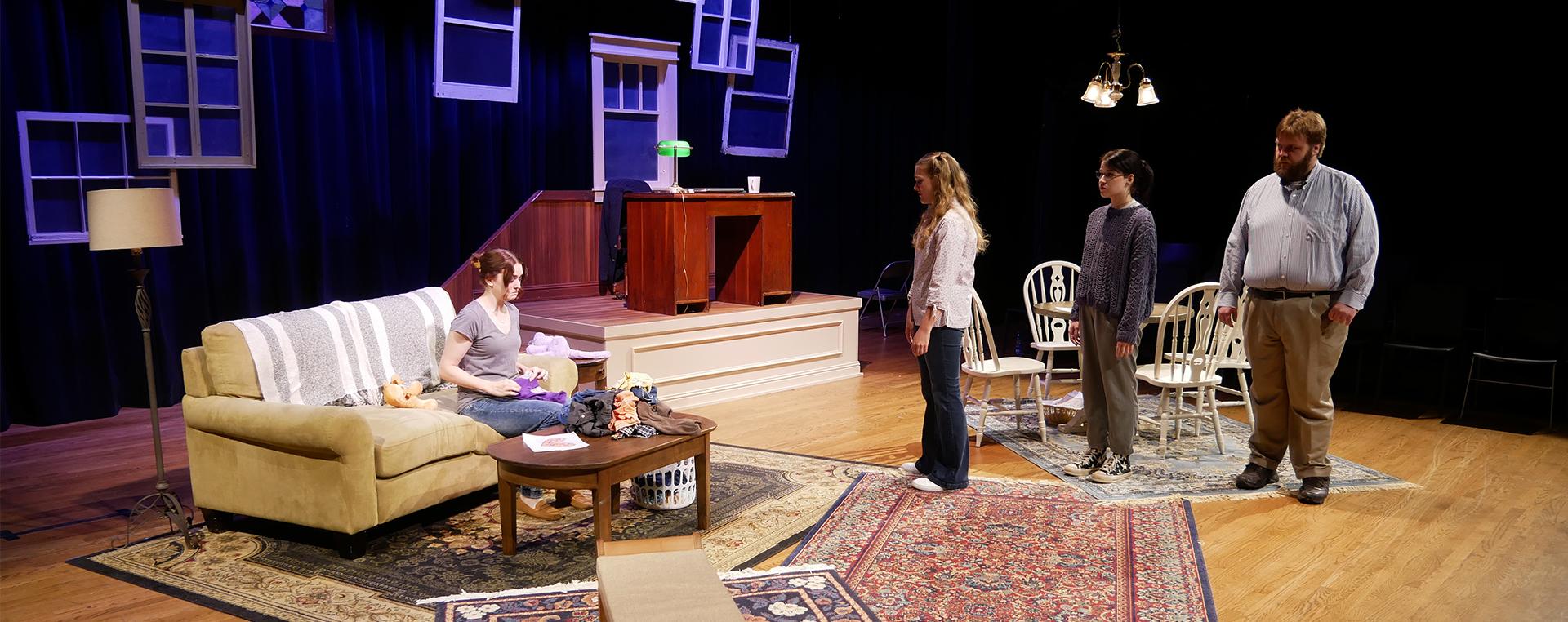 four actors on stage in modern clothes, the set is decorated like a living room