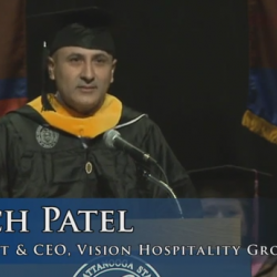Commencement speaker Mitch Patel in cap and gown at podium, President & CEO of Vision Hospitality