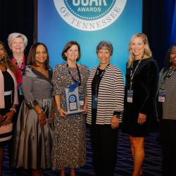 Clomeisha Tumlin, Dr. Beth Norton, Dr. Martina Harris, Dr. Caroline Rogers, Donna Shipley, Dr. Rebecca Ashford, and Dr. Wendolyn Davis stand side by side while Dr. Rogers holds her SOAR award.