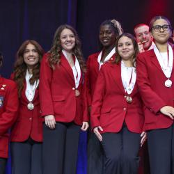 Eight young men and women in red SkillsUSA jackets hold medals.