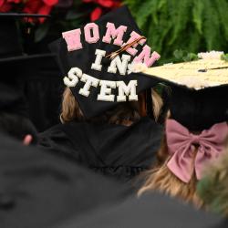 A woman wears a graduation mortarboard that reads "Women in Stem." A woman wears a graduation mortarboard that reads "Women in Stem."