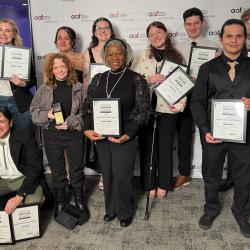 10 ChattState students in formal clothing hold ADDY awards in front of an American Advertising Federation backdrop.