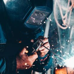 A person is seen welding. Image credit: Christopher Burns, via Usplash.