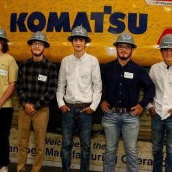 students wearing hard hats in front of Komatsu sign