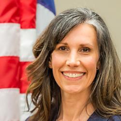 headshot of a woman next to a US flag