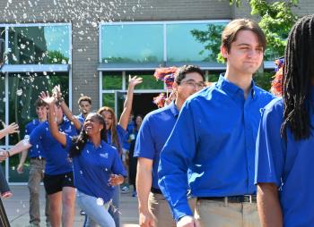 Students in Blue SkillsUSA shirts queue to board a bus to Atlanta. In the background, two young women reach for bubbles in the air as they celebrate. Students in Blue SkillsUSA shirts queue to board a bus to Atlanta. In the background, two young women reach for bubbles in the air as they celebrate.