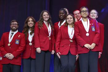 Eight young men and women in red SkillsUSA jackets hold medals.