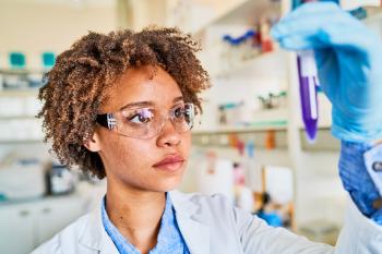 A Medical Laboratory Technician in a white lab coat looks at a medical sample in a plastic tube. A Medical Laboratory Technician in a white lab coat looks at a medical sample in a plastic tube.