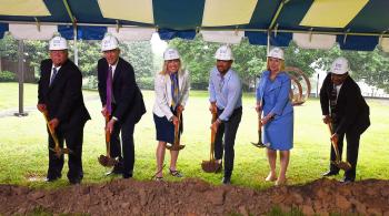 men & women with shovels breking ground